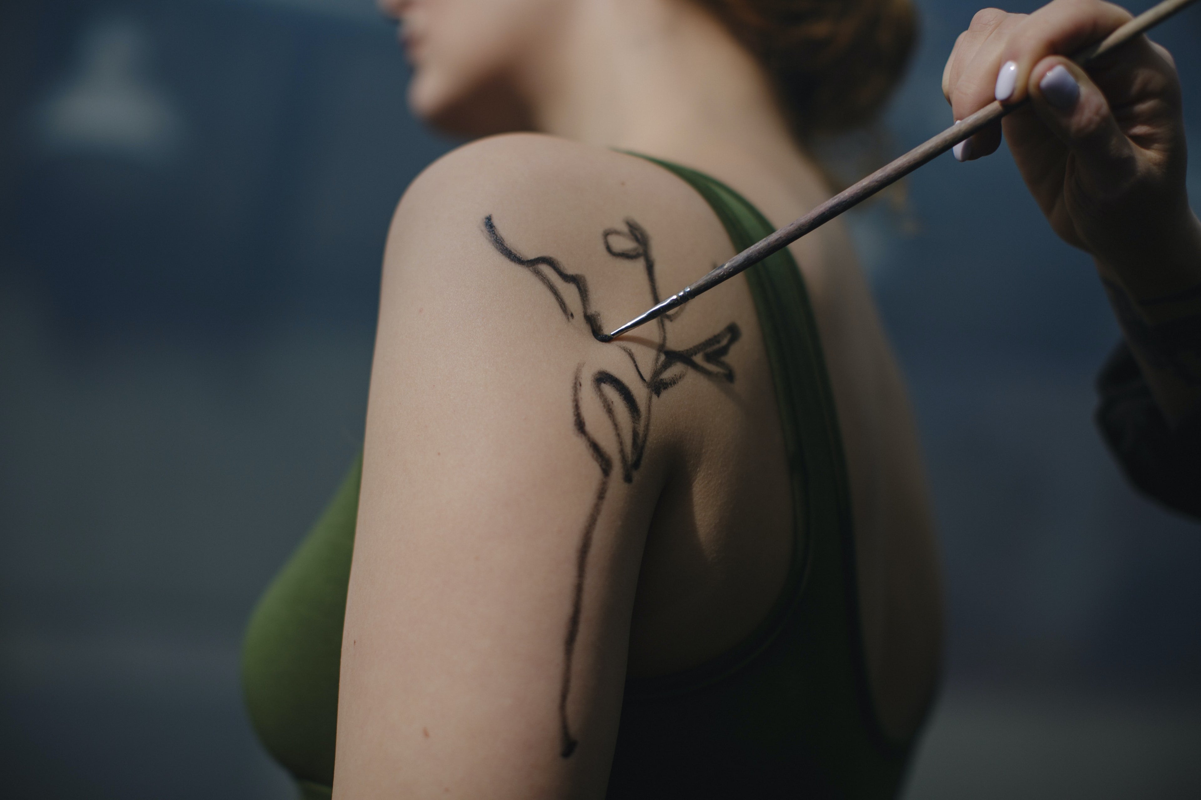 Cotton pad lifting a fading temporary tattoo from skin with Sting-Less remover