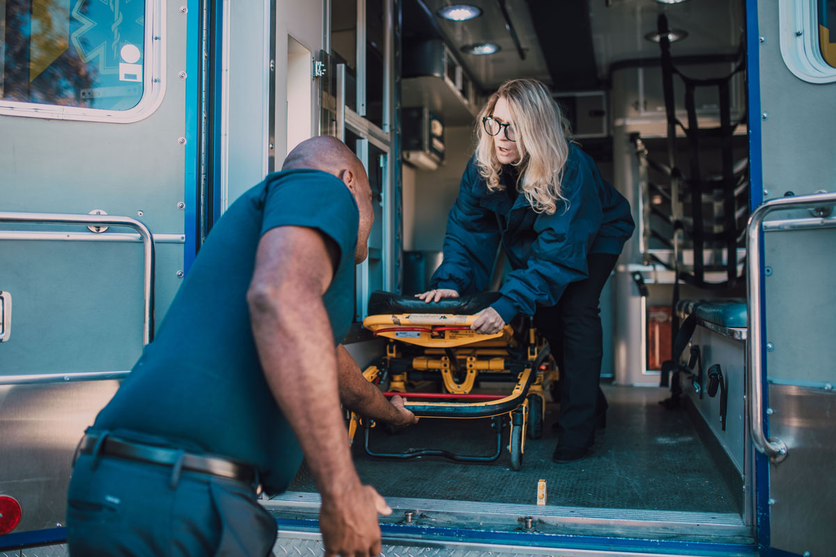 Paramedics loading a stretcher into an ambulance