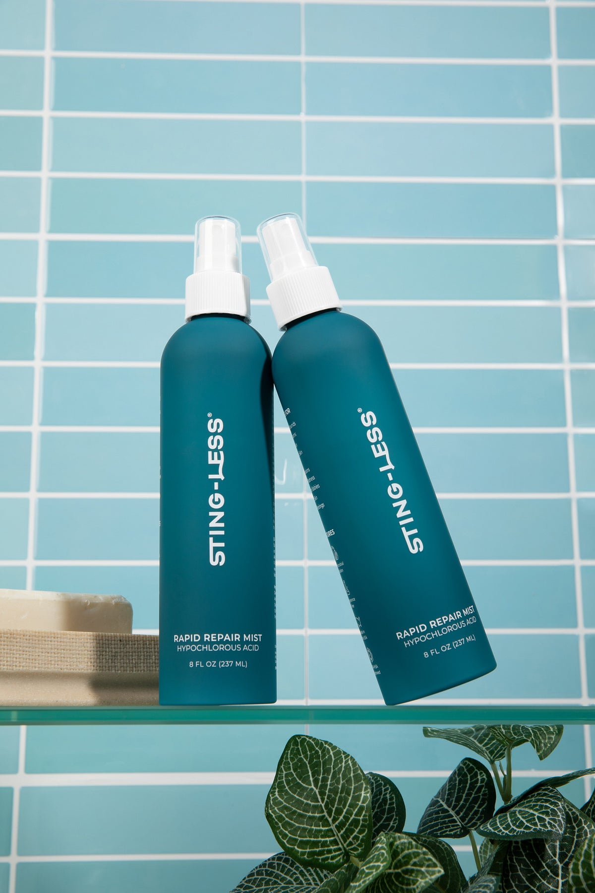 Two Sting-Less Rapid Repair Mist bottles on a glass bathroom shelf