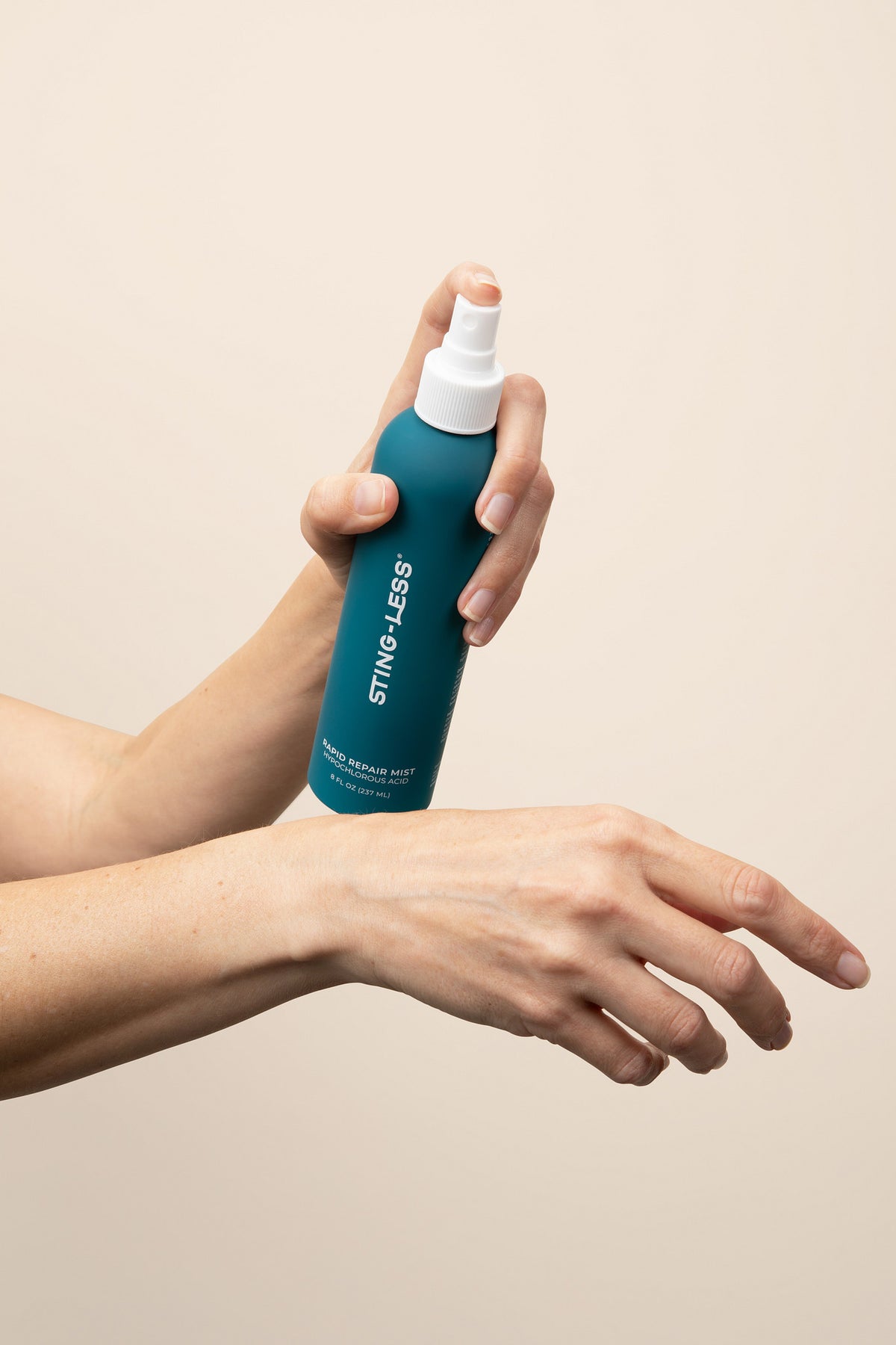 Hand spraying Sting-Less Rapid Repair Mist onto the back of the other wrist
