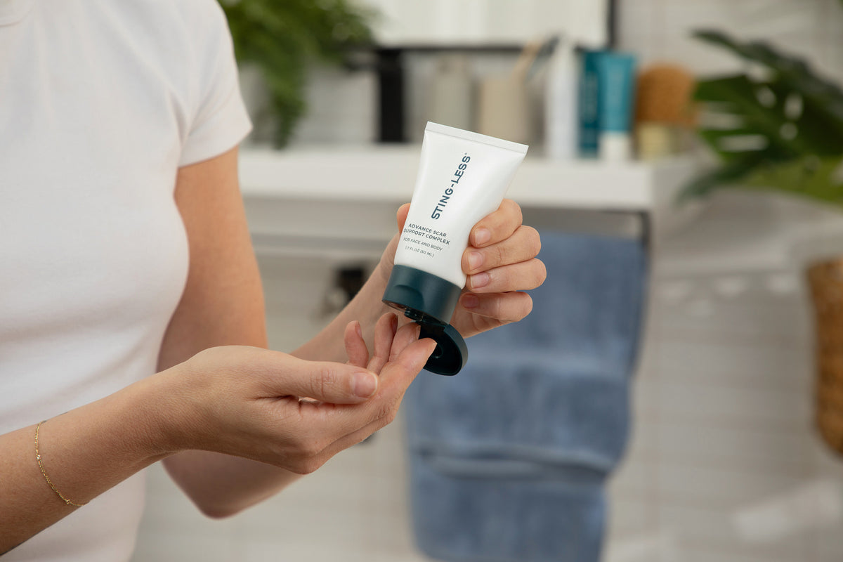 Woman squeezing Sting-Less Scar Gel onto her fingertips in a bathroom